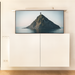 TV mounted on a wall displaying an island scene, below a white cabinet.